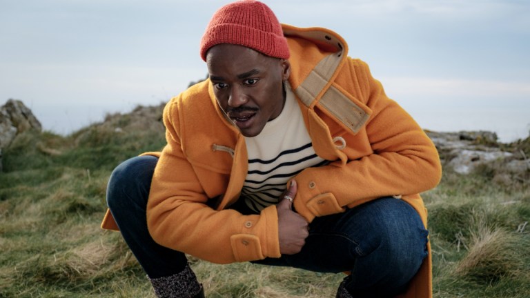 Ncuti Gatwa as the Doctor wearing a yellow duffel coat and an orange hat in Doctor Who episode "73 Yards"