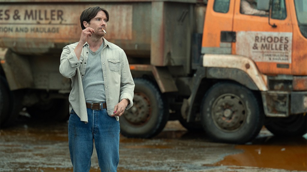 A man smoking next to a dumptruck